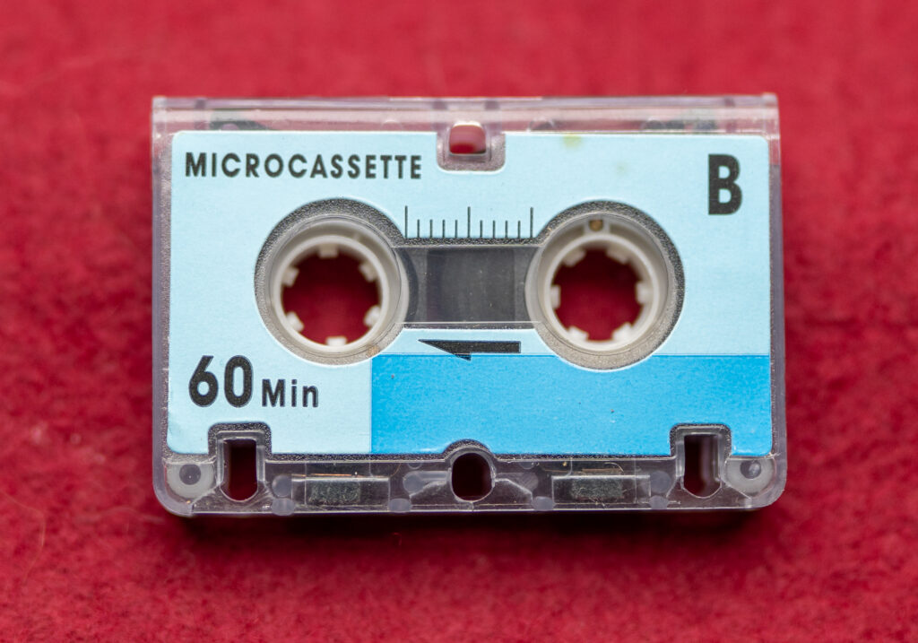 close up product photograph of a microcassette on a red velvet background